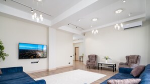 Ein modernes Wohnzimmer mit einem großen Flachbildfernseher, zwei Sofas, einem Couchtisch und einer Topfpflanze.