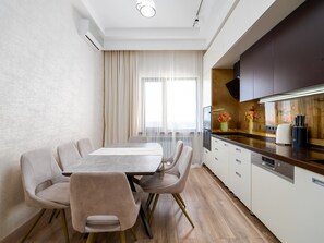Una cocina moderna con comedor, que cuenta con una mesa larga, sillas y vistas a la ciudad a través de amplios ventanales.