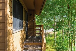 Eine hölzerne Veranda mit einer Bank, mit Blick auf eine üppige, grüne Landschaft.