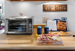 Eine Küchenzeile mit Toaster, Kaffeemaschine, Schneidebrett mit Lebensmitteln und einem Schild mit der Aufschrift 'café latte'.