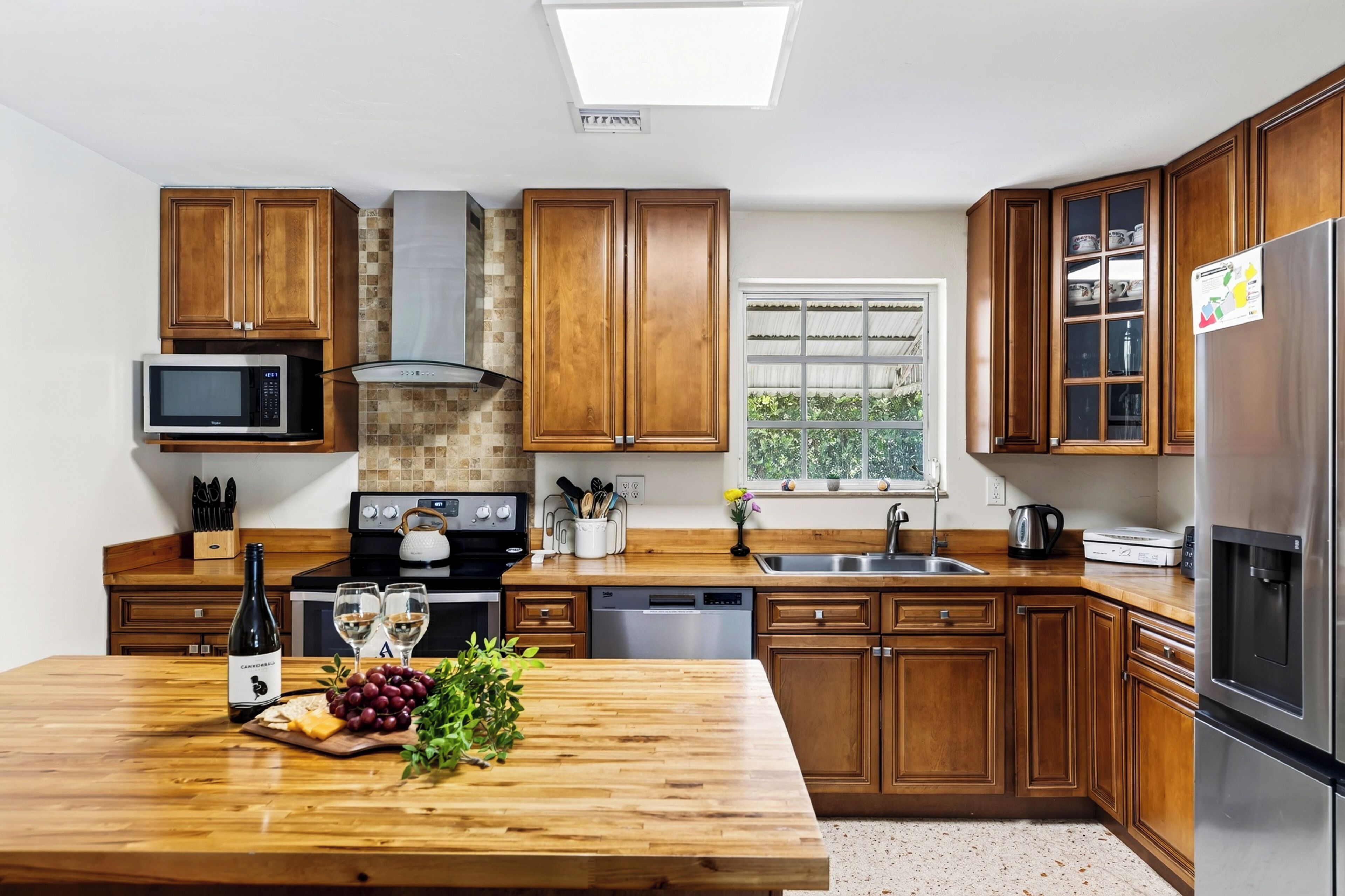 A modern kitchen with wooden cabinets, a built-in microwave, a gas stove, a dishwasher, and a stainless steel refrigerator.