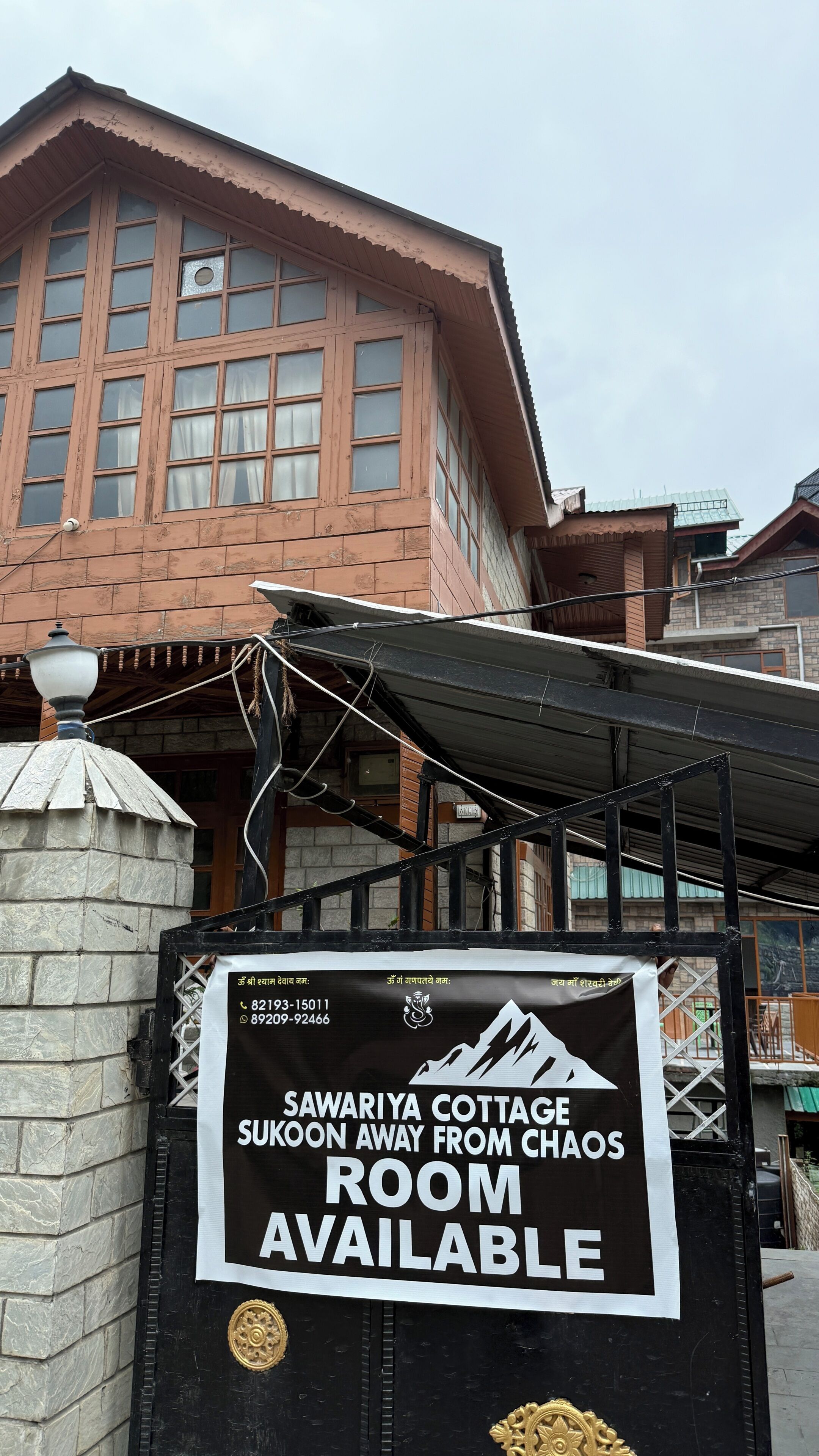 A signboard advertising a room for rent at Sawariya Cottage, with contact numbers and a mountain graphic.