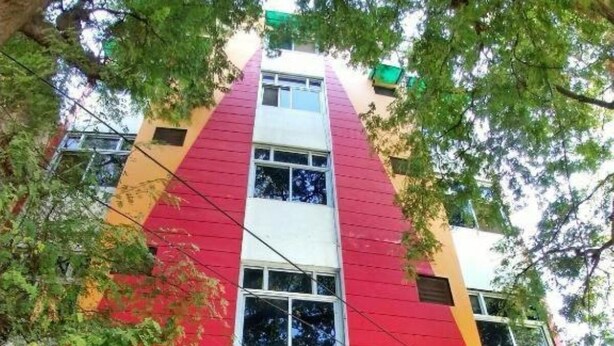 Un edificio con fachada roja y blanca, un letrero que dice 'Panna Patel' y una estatua en la entrada.