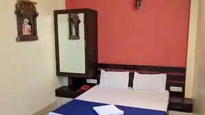 Una habitación de hotel con cama, armario, mesita de noche y ventilador de techo.