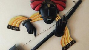 Un adorno de pared que muestra una figura sosteniendo un objeto largo y negro.