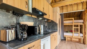 Eine kompakte Küche mit modernen Geräten, Holzschränken und einer eingebauten Sitzbank mit Matratze.