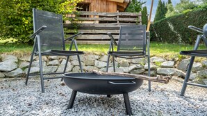 Ein Grill mit vier Stühlen und einem Tisch in einem Garten.