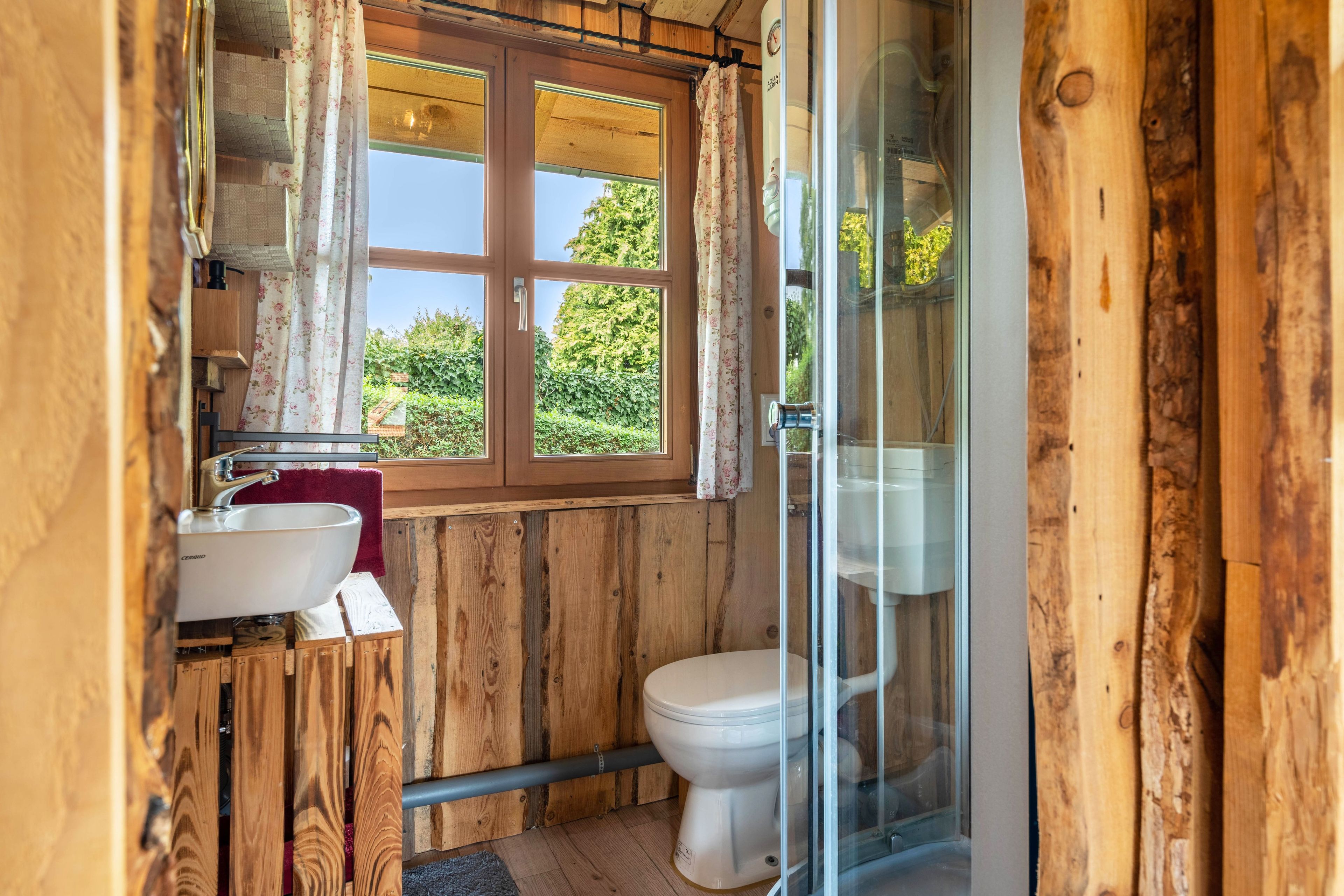 Ein Badezimmer einer Holzhütte mit Fenster, Waschbecken und Toilette.