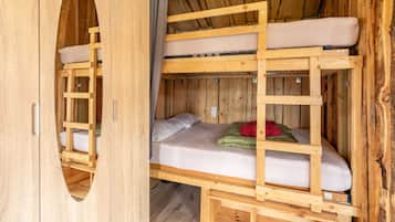 A wooden bunk bed room with a ladder, a mattress, and a blanket.