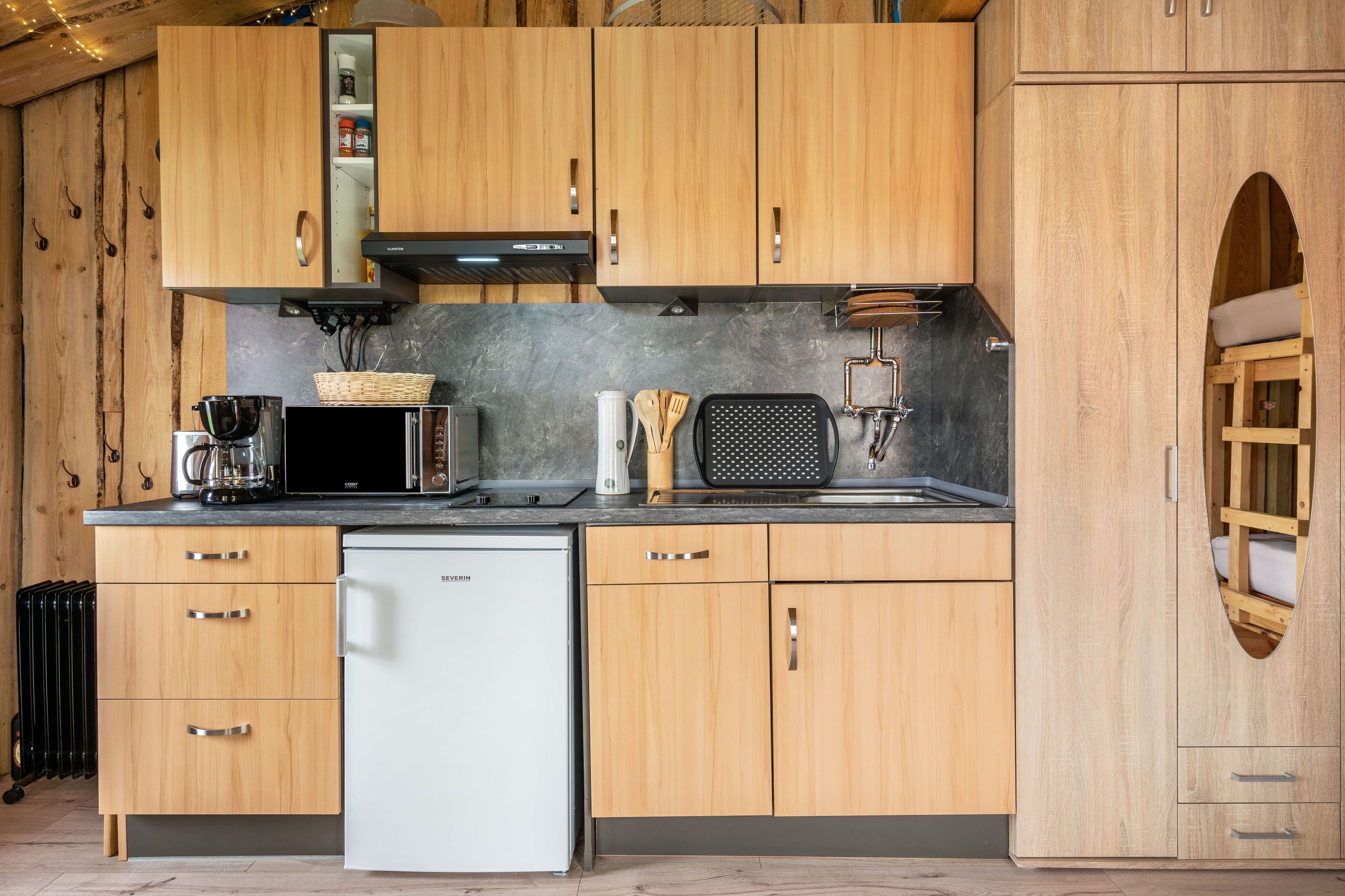 A compact kitchen with wooden cabinets, a white dishwasher, and a microwave.