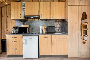 A compact kitchen with wooden cabinets, a white dishwasher, and a microwave.