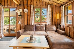 A wooden interior with a sofa, a table with a decorative item, and a clock on the wall.