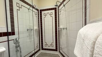 Un bagno moderno con cabina doccia in vetro, pareti piastrellate e soffione.