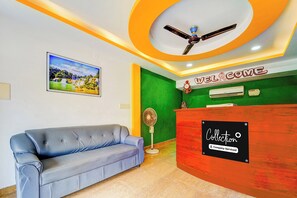 A reception area with a blue sofa, a red reception desk, and a ceiling fan.