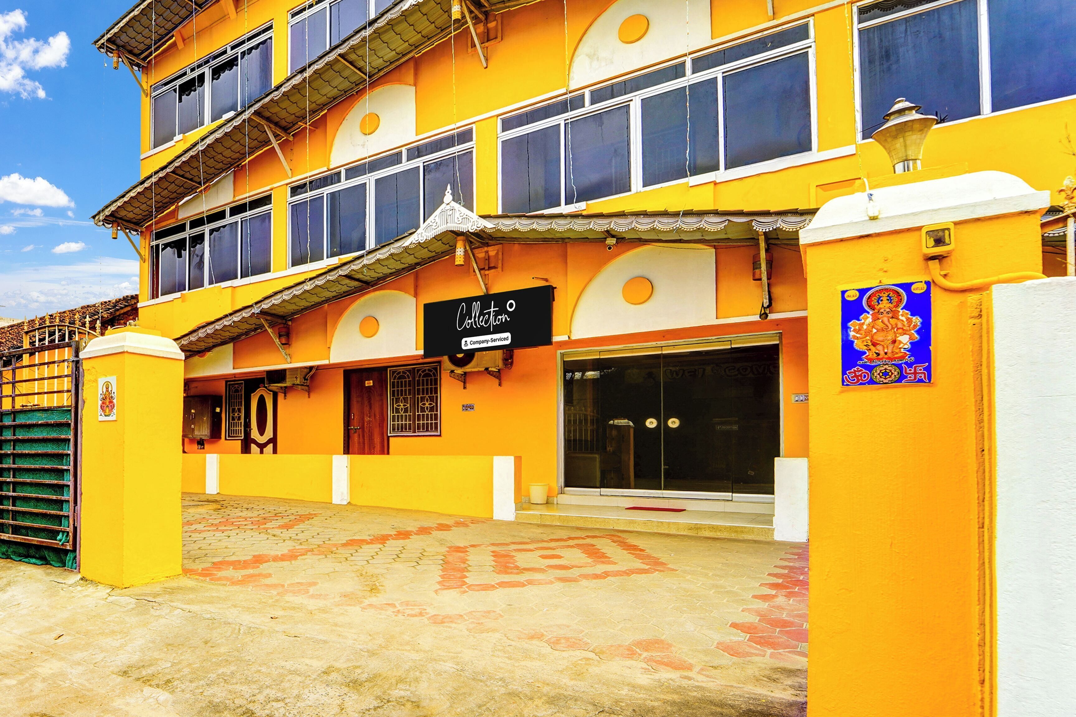 A multi-story building with a yellow facade, a signboard, and a large entrance.