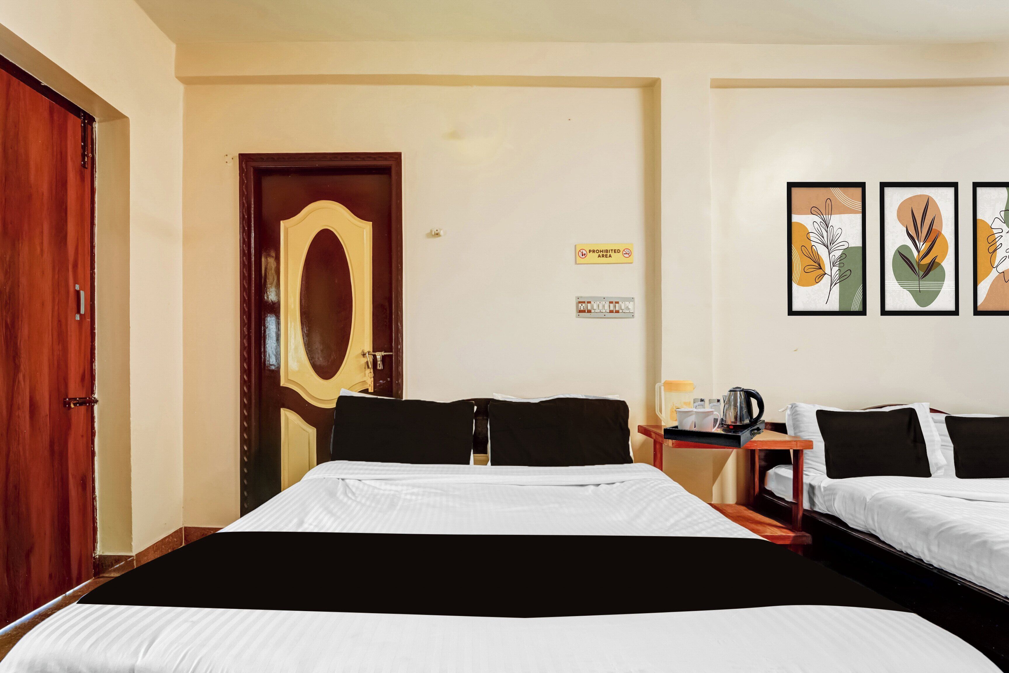 A hotel room with two beds, a wooden door, a wall-mounted light switch, and a 'Prohibited Area' sign.