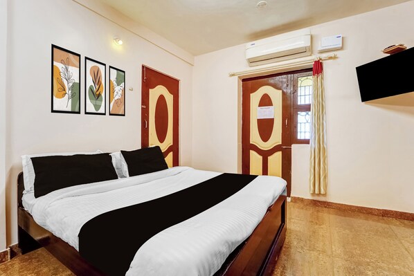 A hotel room with a bed, a wall-mounted TV, and framed artwork.