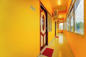 Un pasillo con paredes amarillas, un letrero de salida de incendios y una puerta con un panel de vidrio decorativo.