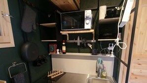 Una cocina compacta con microondas, pileta y alacenas de madera.
