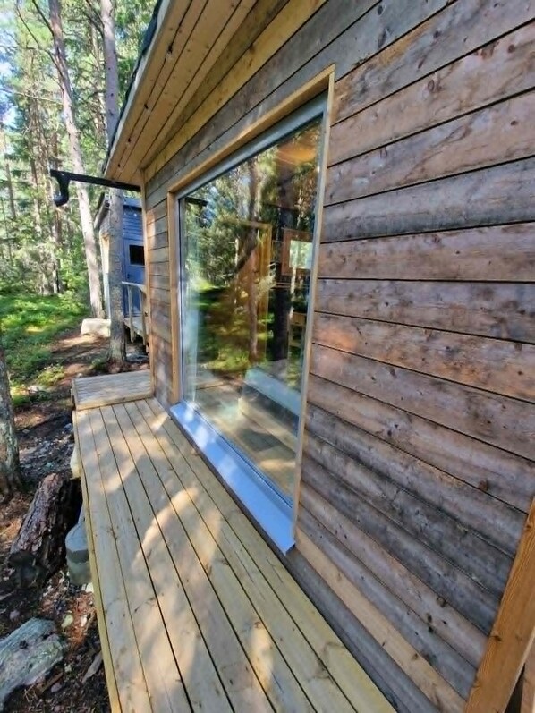 A wooden cabin with a glass door and a deck.