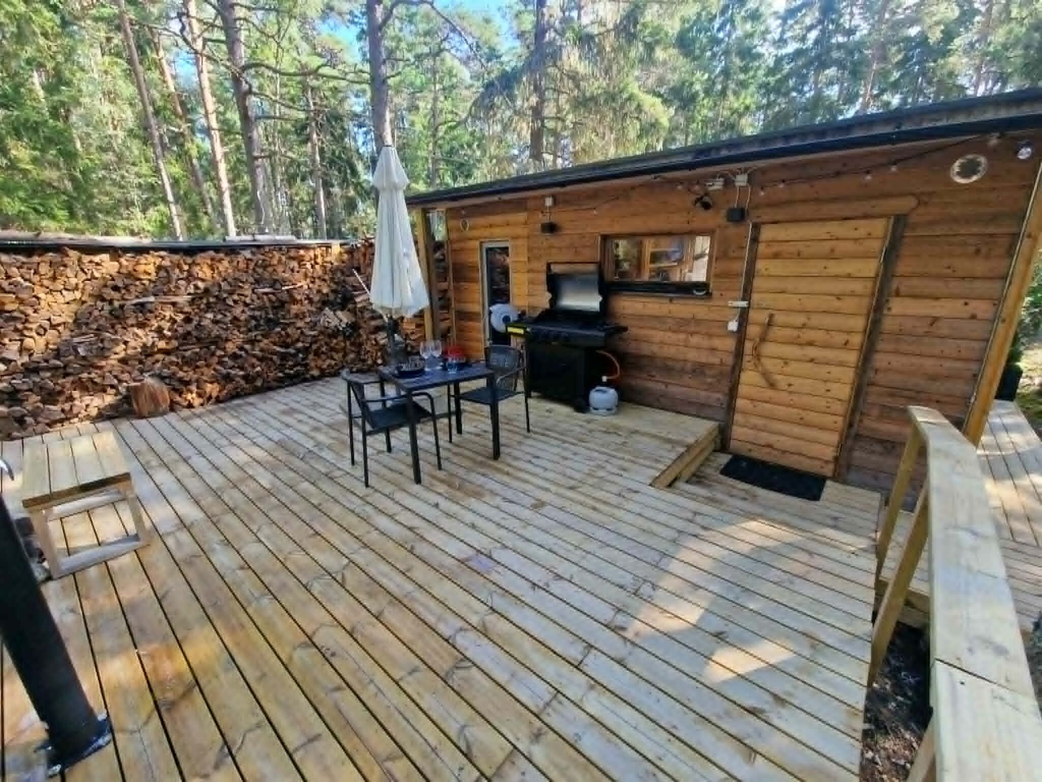 A wooden deck with a table and chairs, a barbecue grill, and a stone wall.