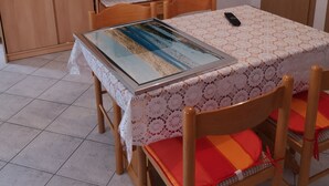 Un comedor con una mesa, sillas, un televisor montado en la pared y un armario.