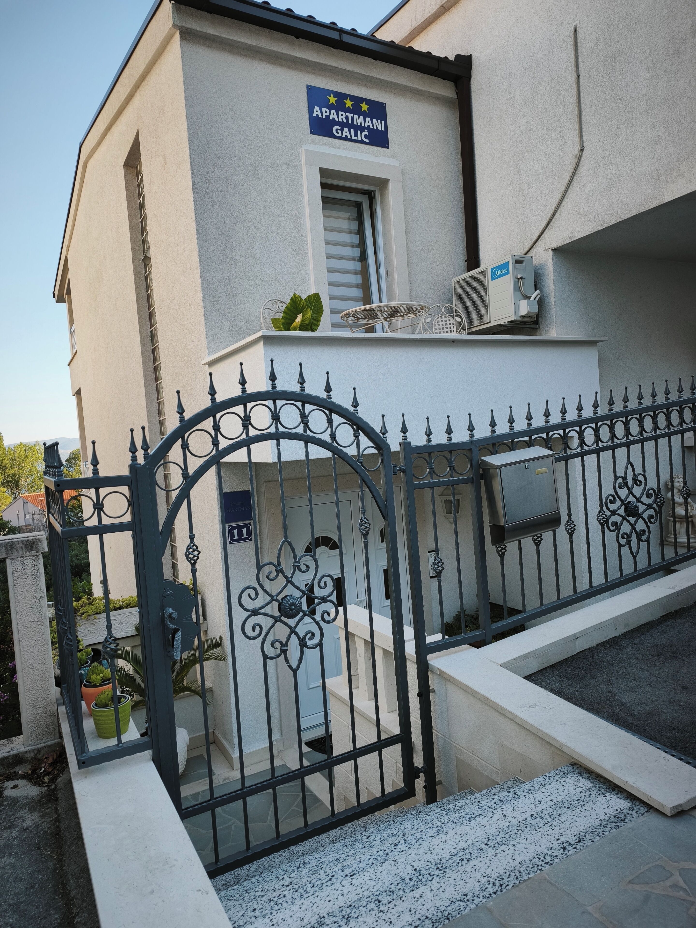 Un immeuble avec une enseigne indiquant « APARTMANI GALIC » et une entrée fermée par un portail.
