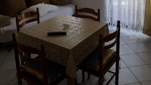 Un comedor con una mesa, sillas, un sofá y una ventana con cortinas ligeras.