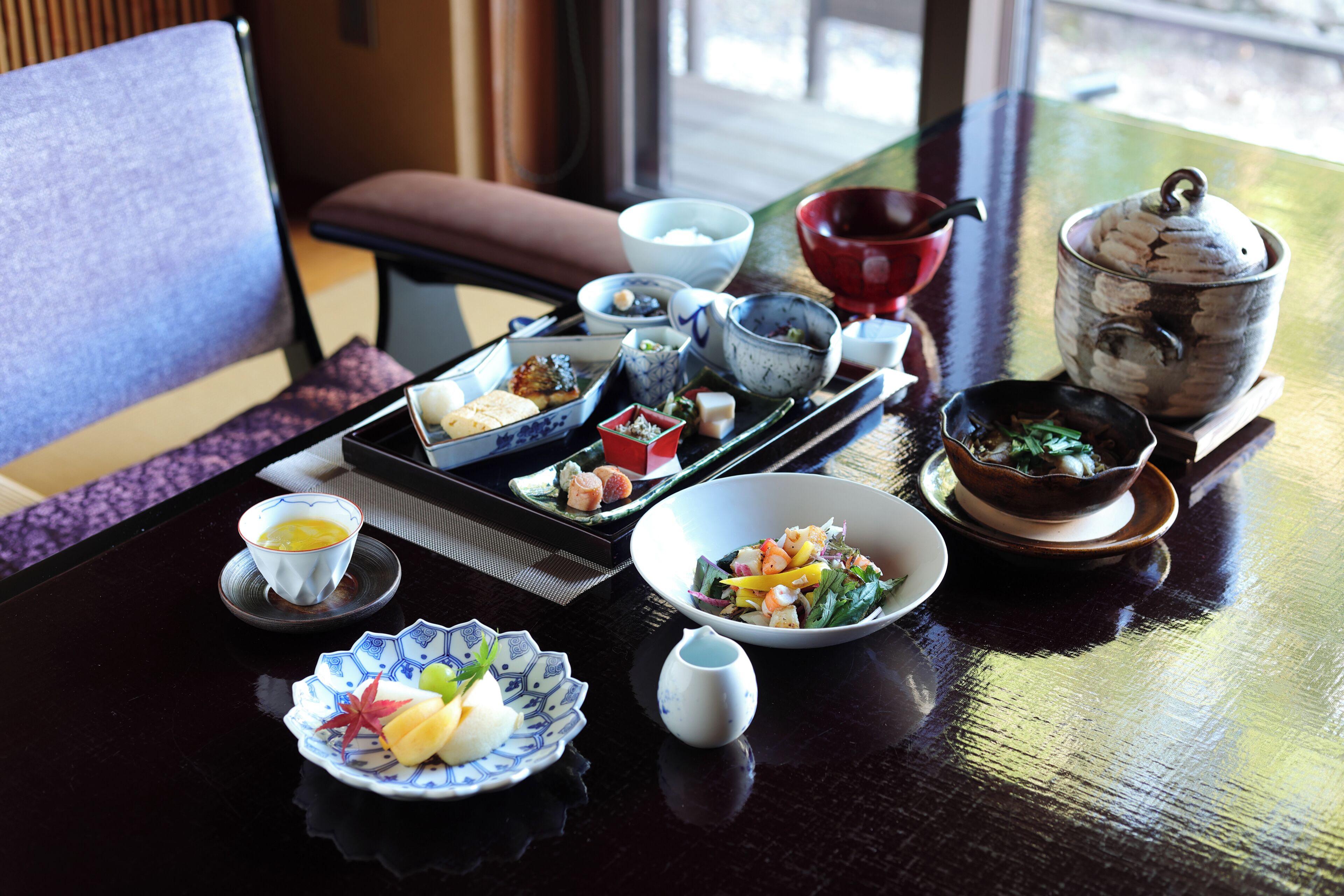 A dining table with various dishes, including sushi, sashimi, and a bowl of salad.