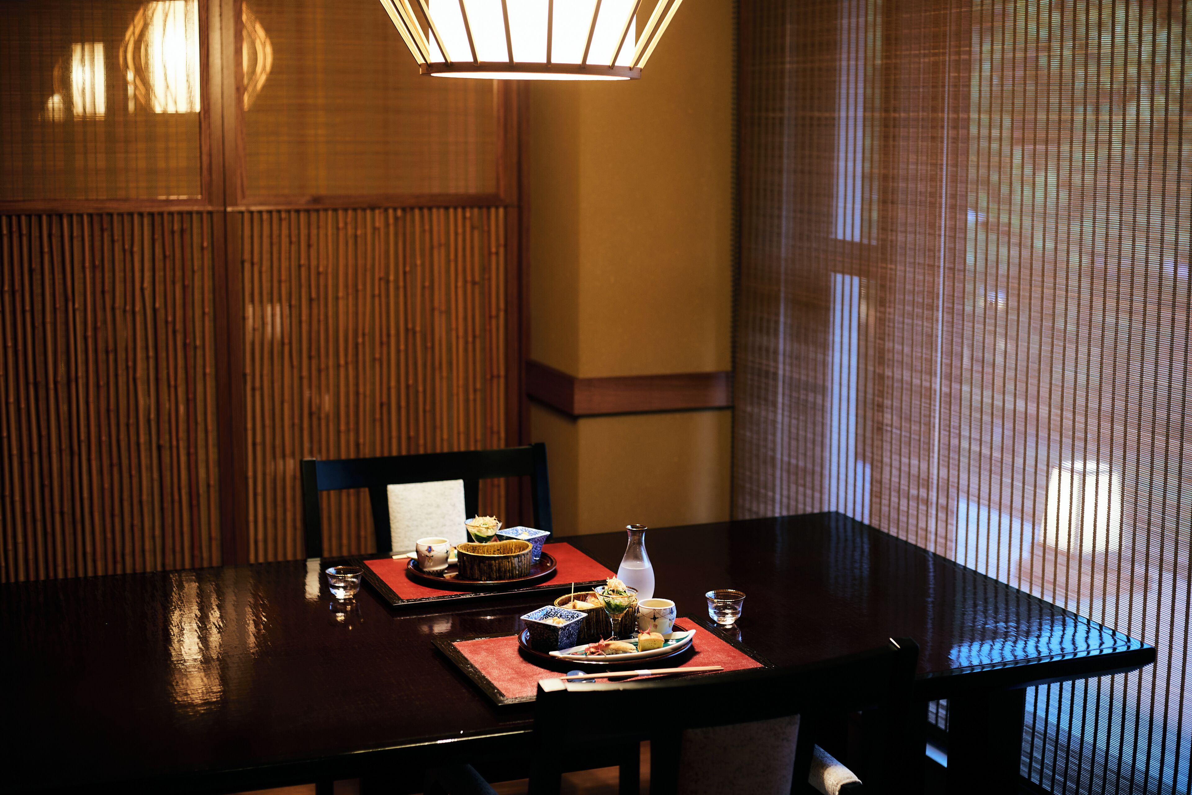 A dining table set with plates, bowls, and a bottle, with chairs around it.