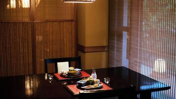 A dining table set with plates, bowls, and a bottle, with chairs around it.
