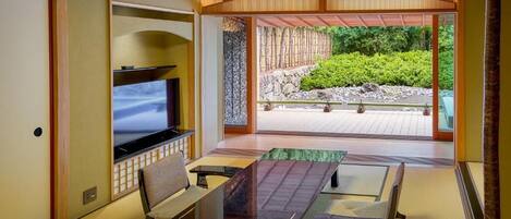 A traditional Japanese-style room with tatami flooring, a low table, and a television.
