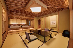 Una habitación japonesa tradicional con suelo de tatami, una mesa baja y un sofá con cojines.