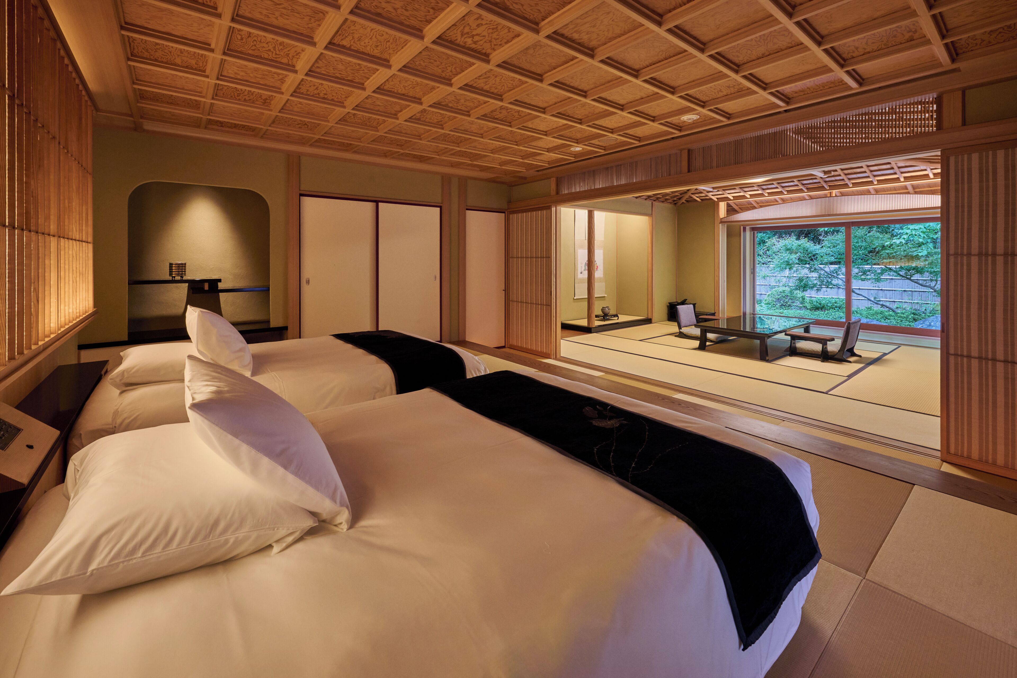 A traditional Japanese-style room with tatami flooring, a sliding door leading to a balcony, and a view of greenery outside.