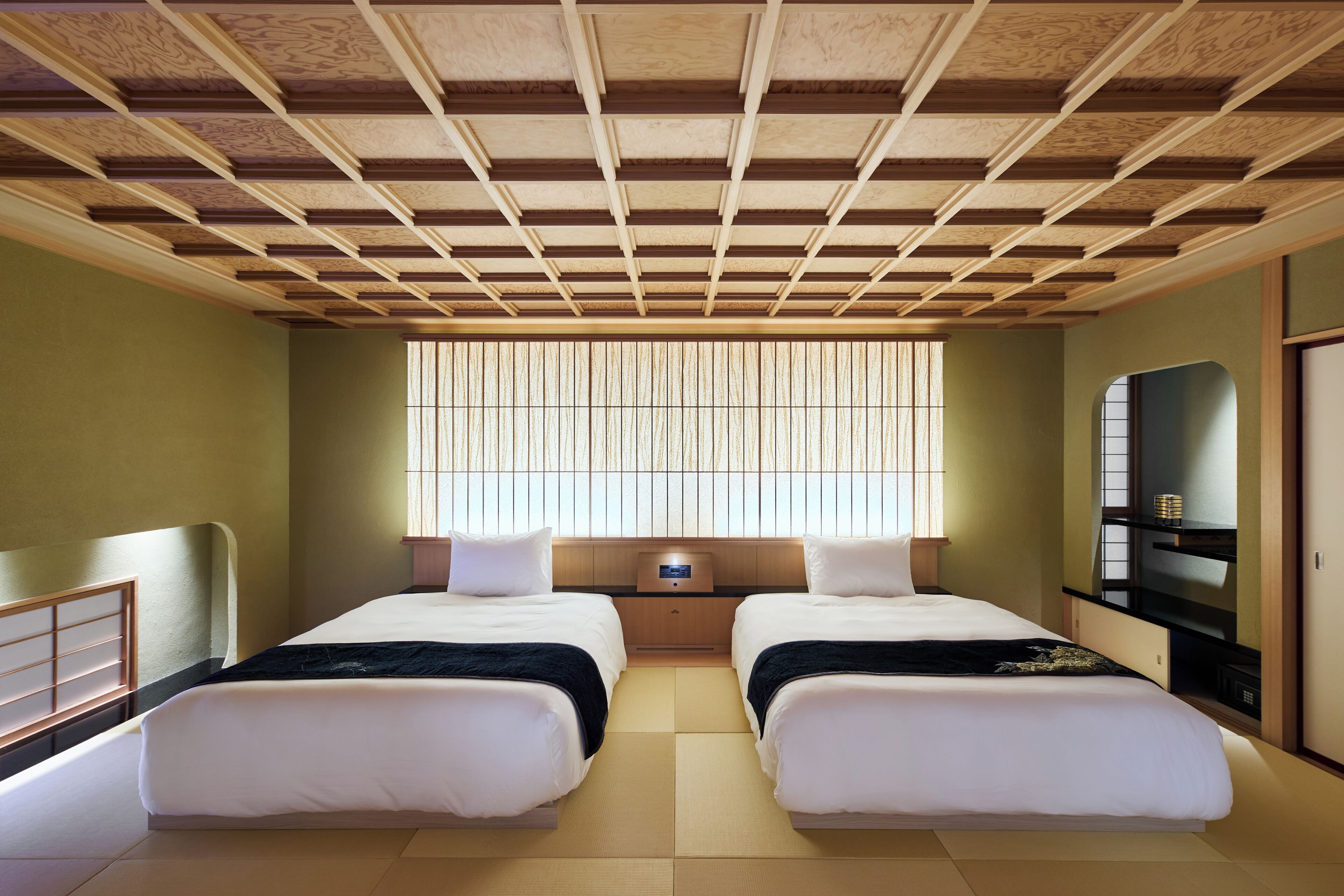 Una habitación con dos camas, una ventana con persianas verticales, una mesita y un televisor sobre un mueble.