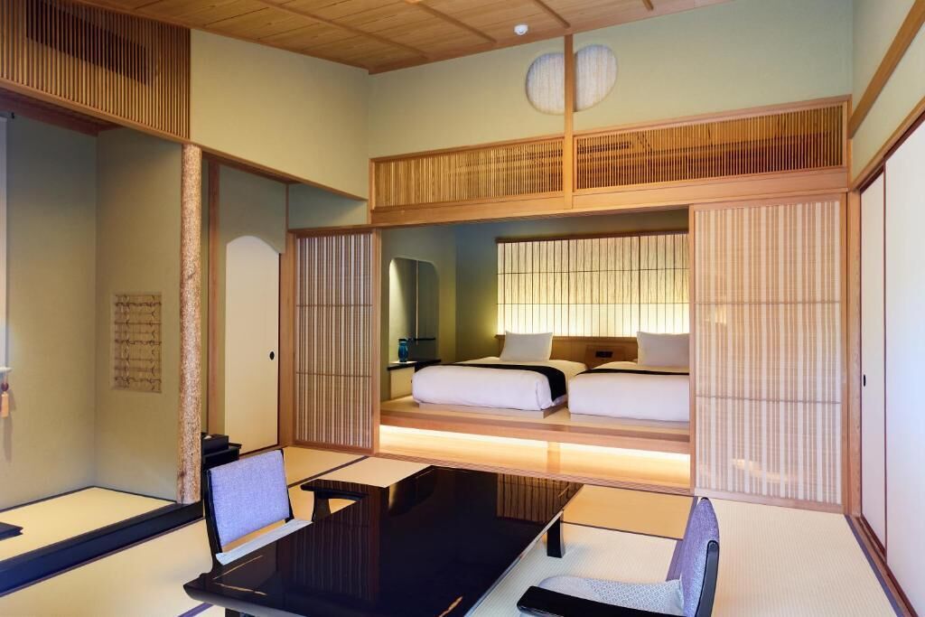 Una habitación tradicional japonesa con suelo de tatami, una cama baja de madera y un escritorio con silla.