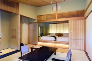 A traditional Japanese-style room with tatami flooring, a low wooden bed, and a desk with a chair.