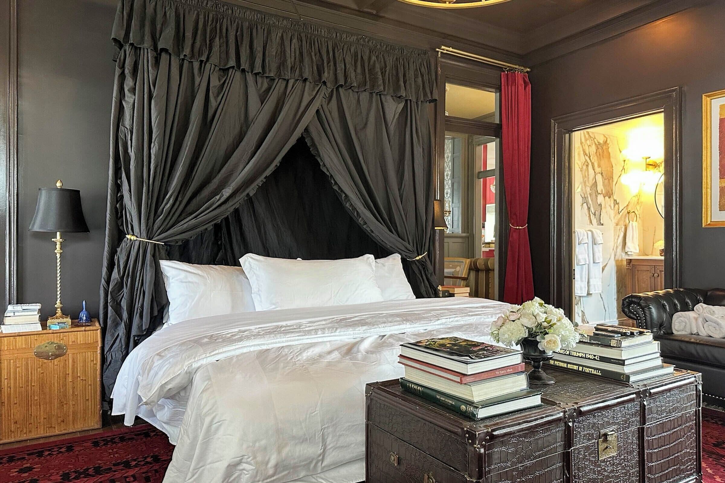 Une chambre à coucher avec un lit, une table de chevet, une commode et un rideau rouge.
