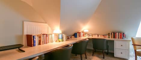 Una habitación con escritorio, sillas, estanterías y un radiador.