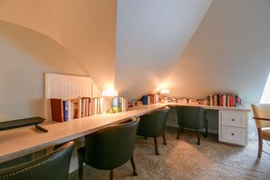 Un bureau équipé d’un pupitre, de chaises, d’étagères et d’un radiateur.