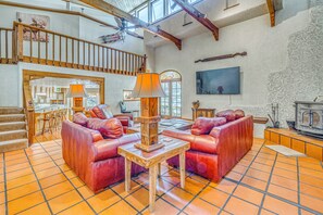 A spacious living area with a high ceiling, a fireplace, and a dining area with a view of the outdoors.