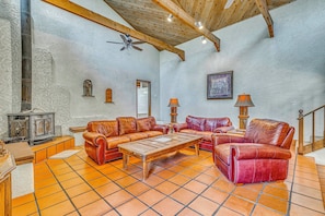 A spacious living room with a high ceiling, a fireplace, leather sofas, a wooden coffee table, and a tiled floor. - Hike & Ski! Quiet Home w/ Solarium in Cloudcroft (Cloudcroft)