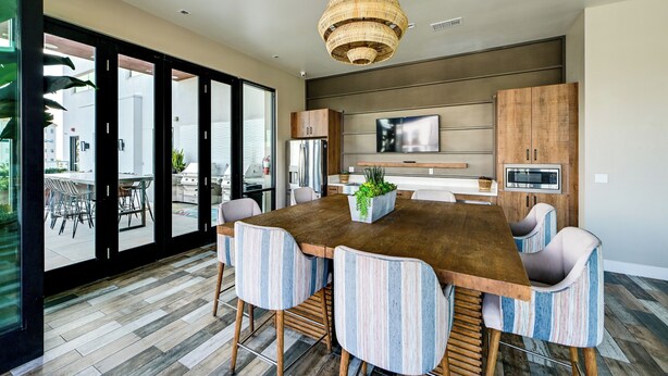 A modern kitchen with a large island, stainless steel appliances, and a hanging light fixture. - Steps to the Sand! Luxury Oceanside Pier Condo (Oceanside)
