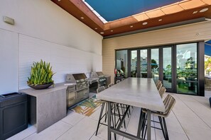 An outdoor kitchen area with a grill, a sink, and a countertop. - Steps to the Sand! Luxury Oceanside Pier Condo (Oceanside)