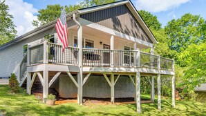 A two-story house with a covered porch and an American flag. - Walk to Dtwn Waynesville! Dual Mtn Havens w/ Decks (Waynesville)