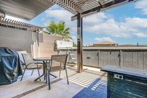 A covered patio area with a table and chairs, a grill, and a wooden fence. - Private Swim Spa & EV Charger! By Tuacahn and more (Santa Clara)