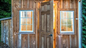 Une structure en bois dotée de deux fenêtres, d’une porte et d’une rambarde en métal.
