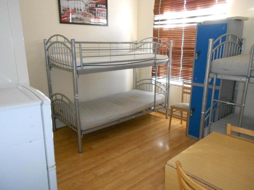 Een slaapkamer met een stapelbed, een houten tafel en een stoel.