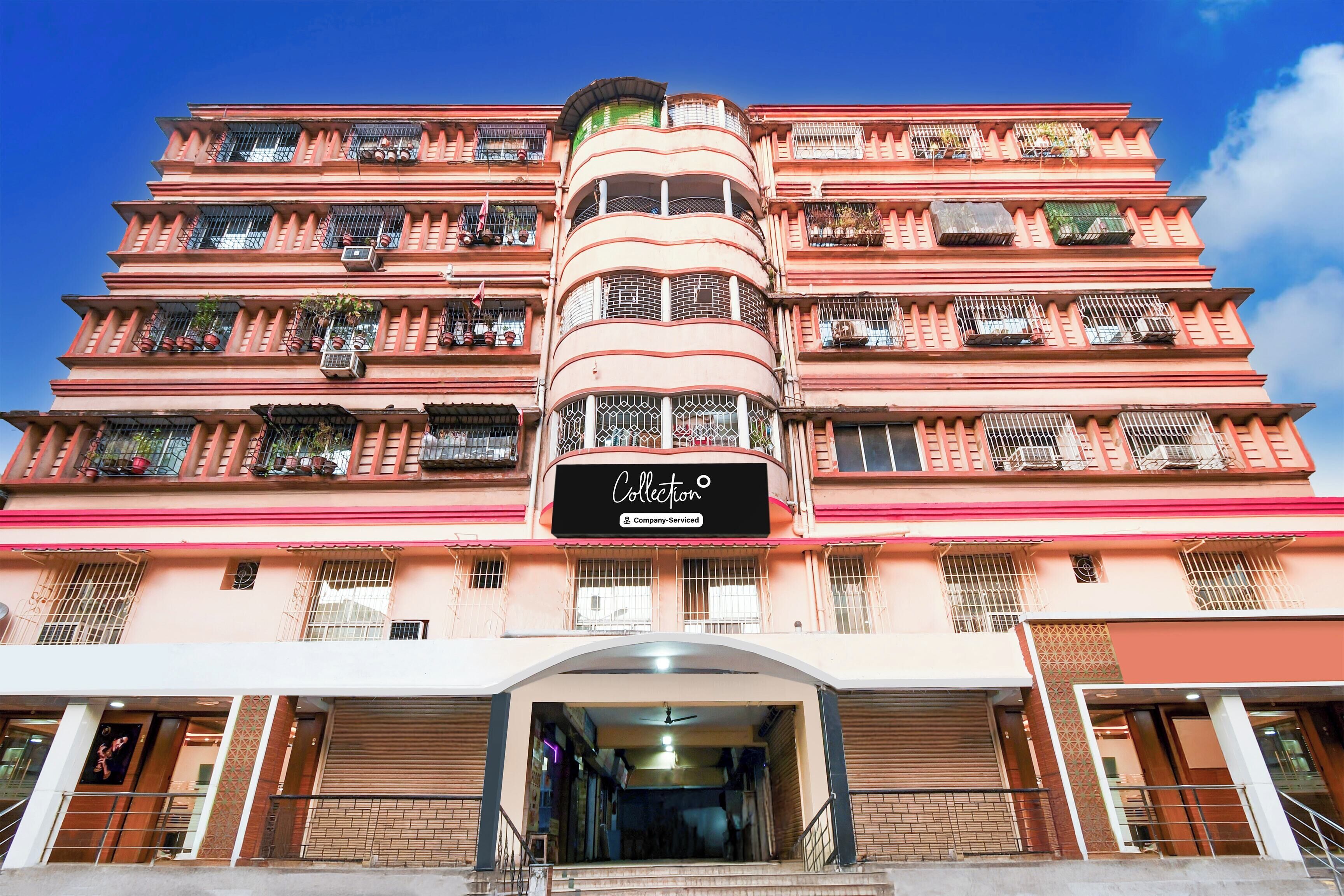 Un edificio de varios pisos con una torre central, balcones con barandillas y un escaparate con señalización.
