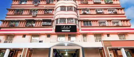 A multi-story building with a central tower, balconies with railings, and a storefront with signage.